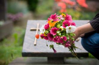 
		Eine Nahaufnahme eines Blumenstraußes vor einem Grabstein auf einem Friedhof
	