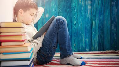 
		Achtjähriges Kind, das zu Hause ein Buch liest. Junge, der auf blauem Hintergrund lernt.
	