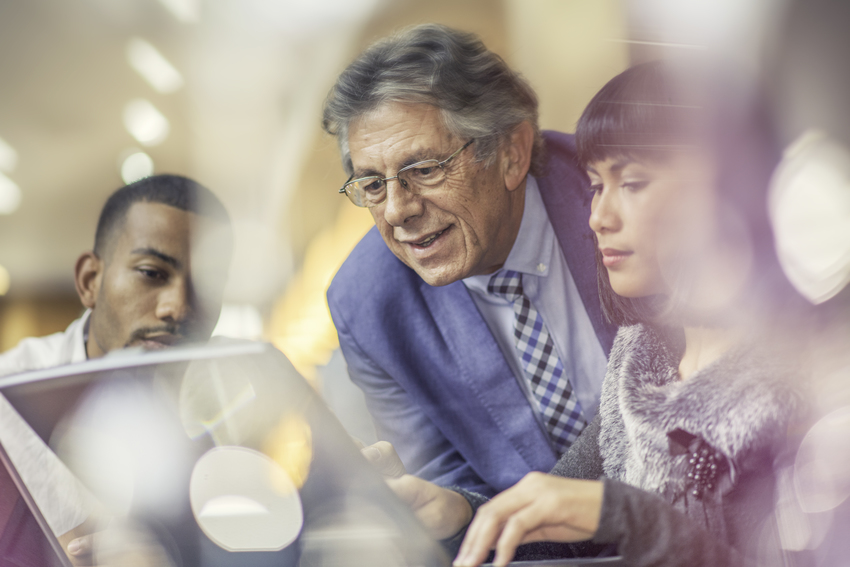 Junge Mitarbeiter helfen einem älterem Kollegen