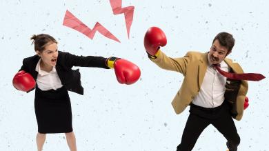 
		Eine Frau und ein Mann im Business-Look haben Boxhandschuhe an und wollen sich attackieren
	