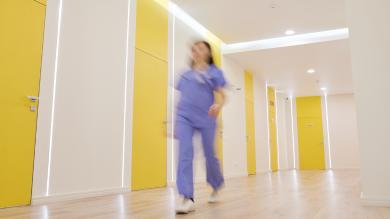 
		Eine Krankenpflegerin läuft durch den Gang eines Krankenhauses
	