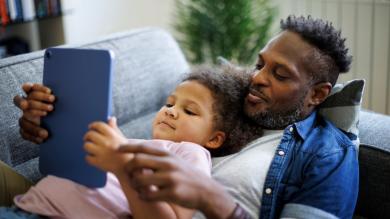 
		Vaer und Kind schauen gemeinsam auf ein Ipad
	