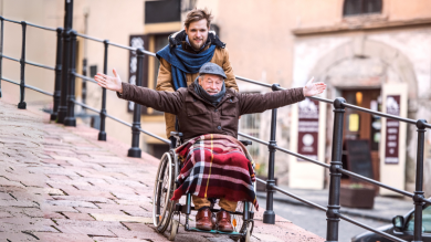 
		Junger Mann schiebt alten Mann im Rollstuhl
	
