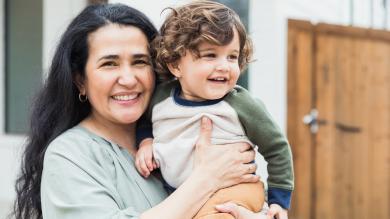 
		Lächelnde Frau mit kleinem Kind auf dem Arm
	