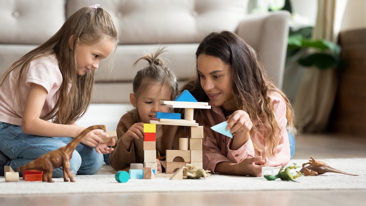 Junge Frau spielt mit zwei Kindern auf dem Boden