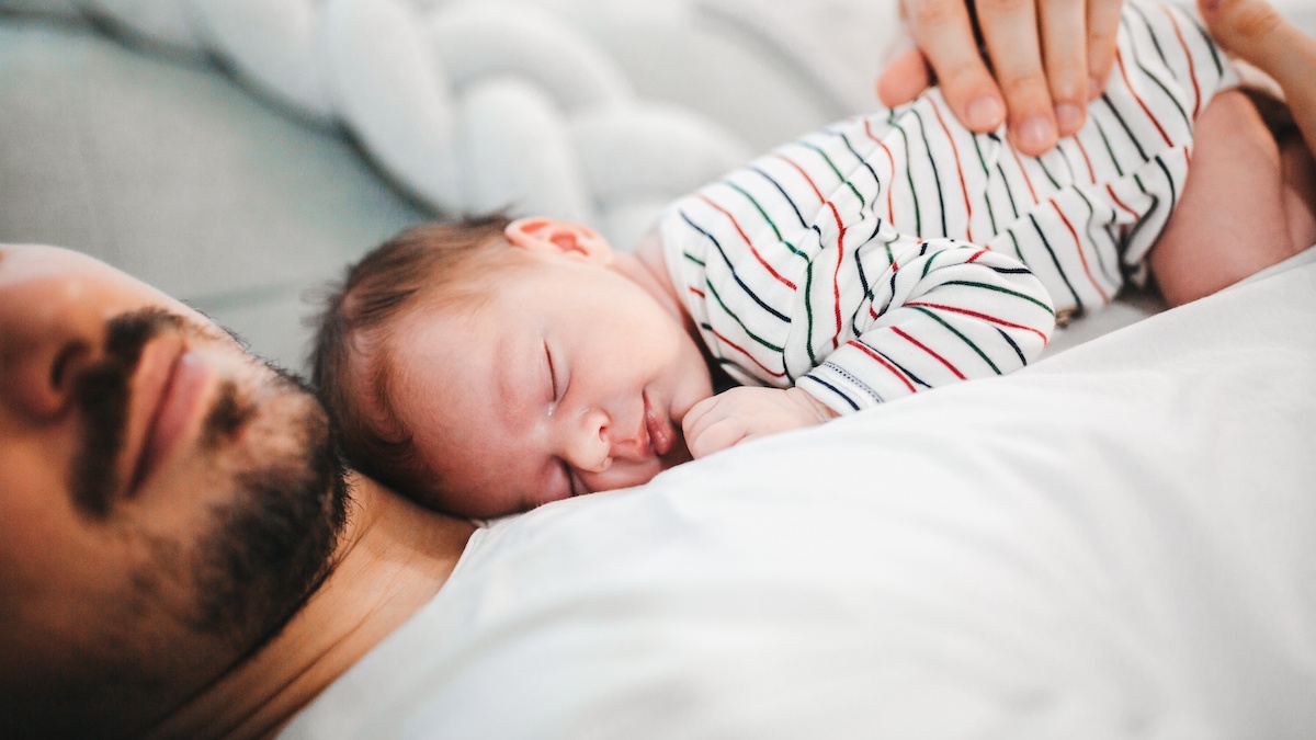 Ein Baby schläft auf der Brust des Vaters