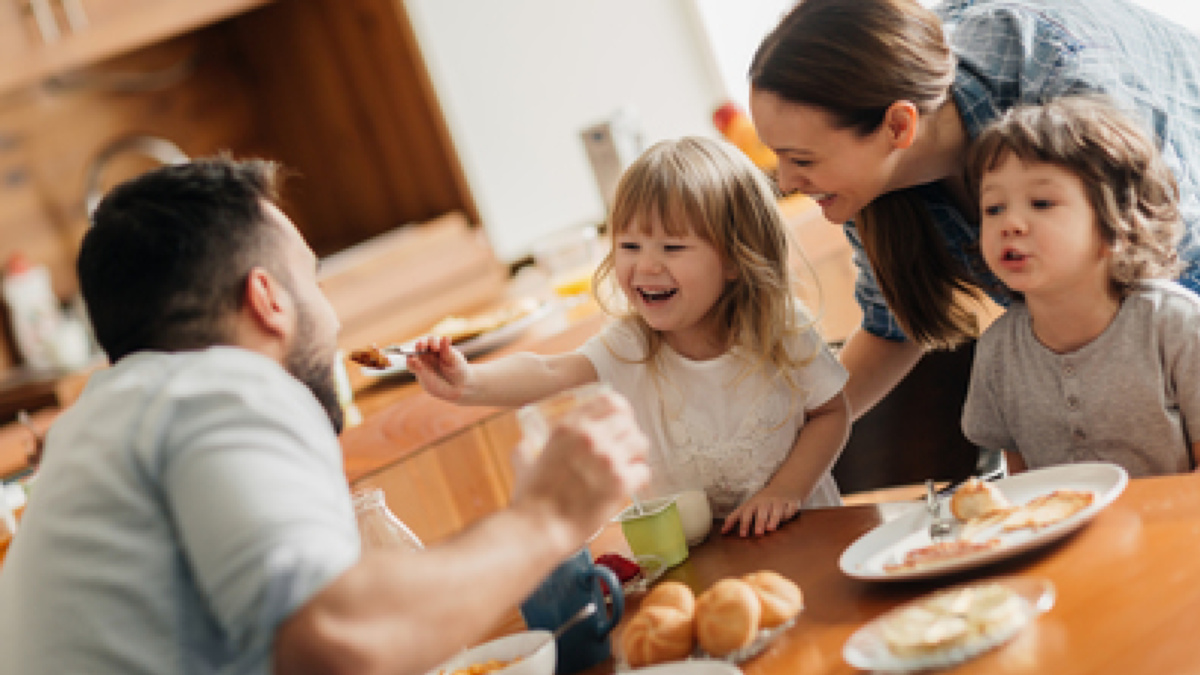 Eine Familie sitzt am Küchentisch und isst gemeinsam