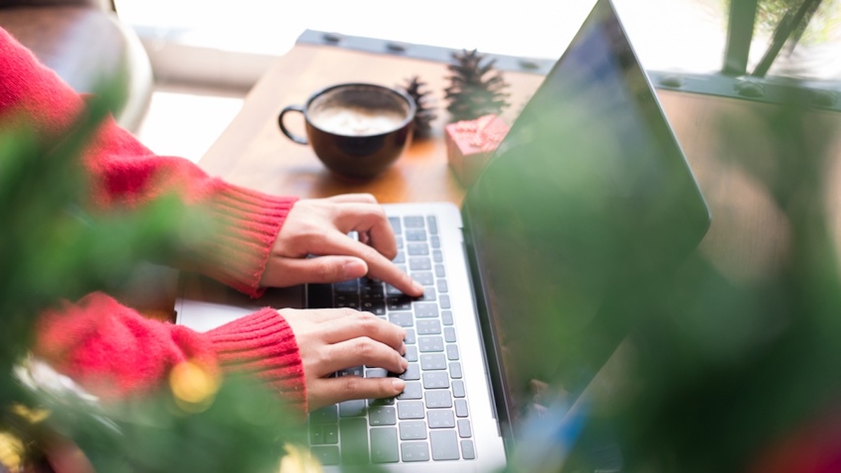 Nahaufnahme von weiblich gelesenen Händen, die auf eine Laptop-Tastatur tippen