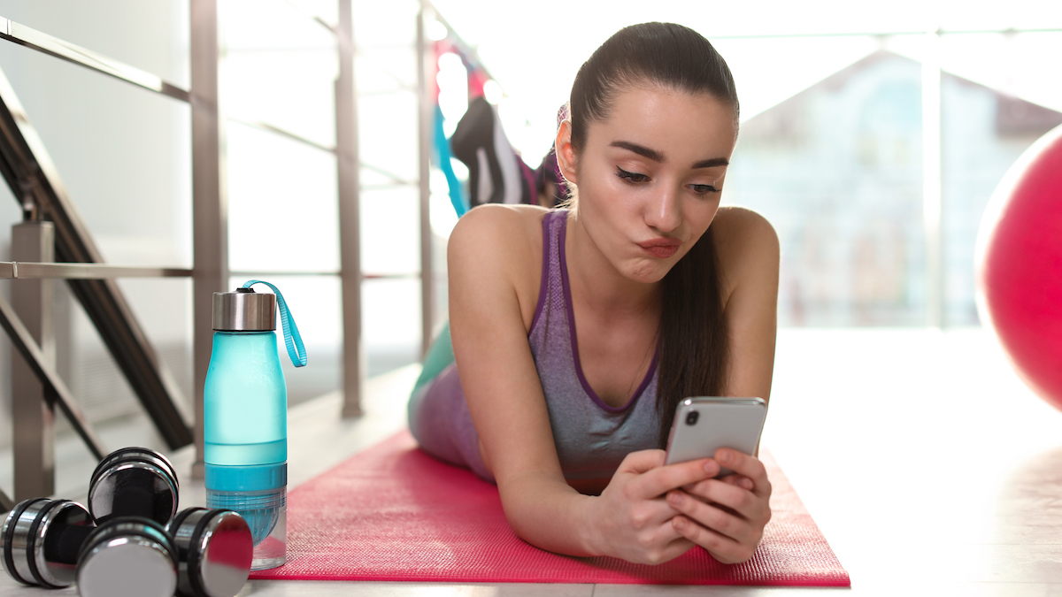 Frau mit Handy faul auf Yogamatte